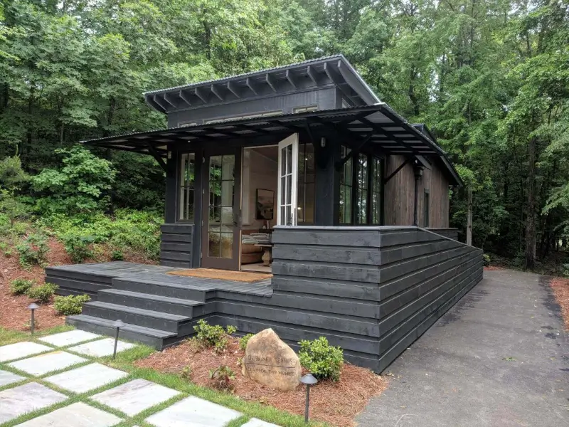 modern manufactured home with black siding and open front porch