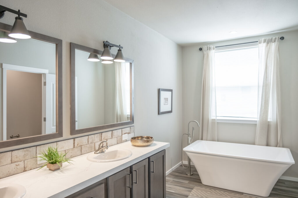 manufactured home bathroom featuring dual vanities and soaking tub
