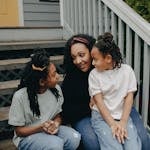 Mother with two daughters enjoying a joyful moment on the porch steps.